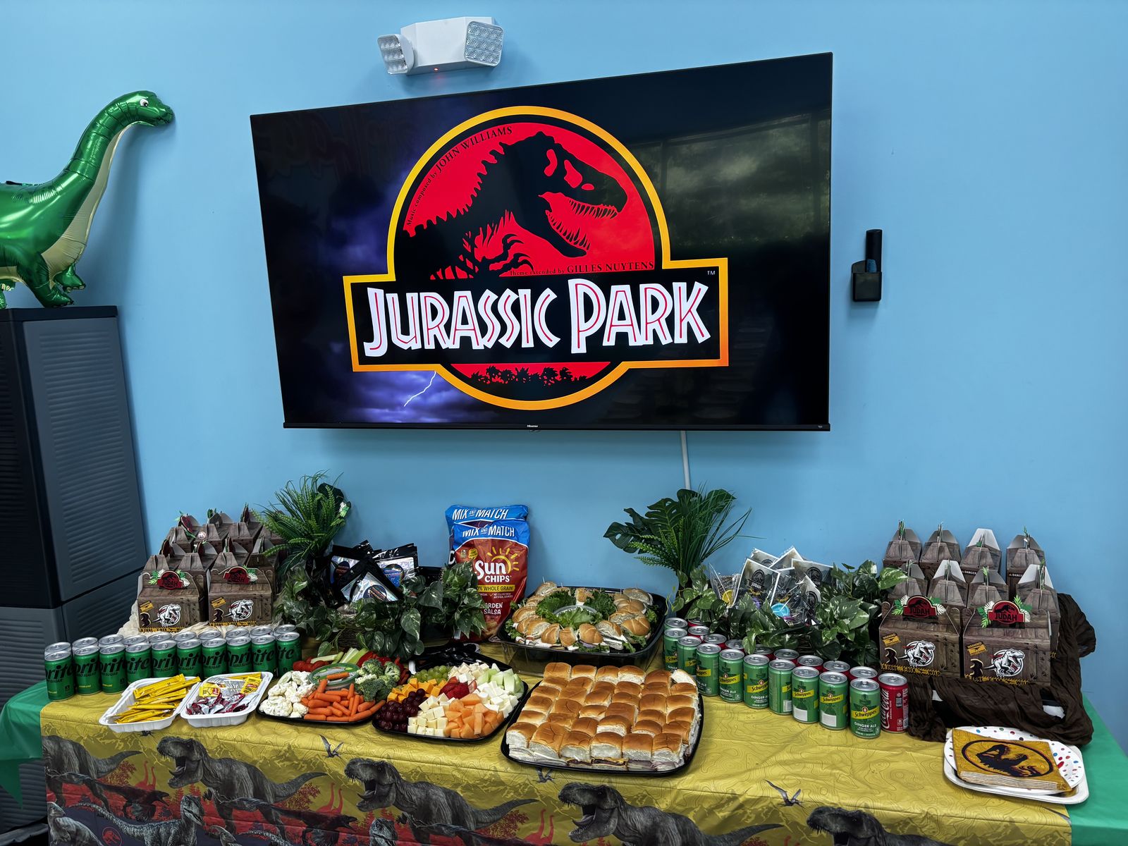 Dinosaur-themed birthday party table with food platters, drinks, and favor boxes in a private party room at Hyper Kidz Rockville